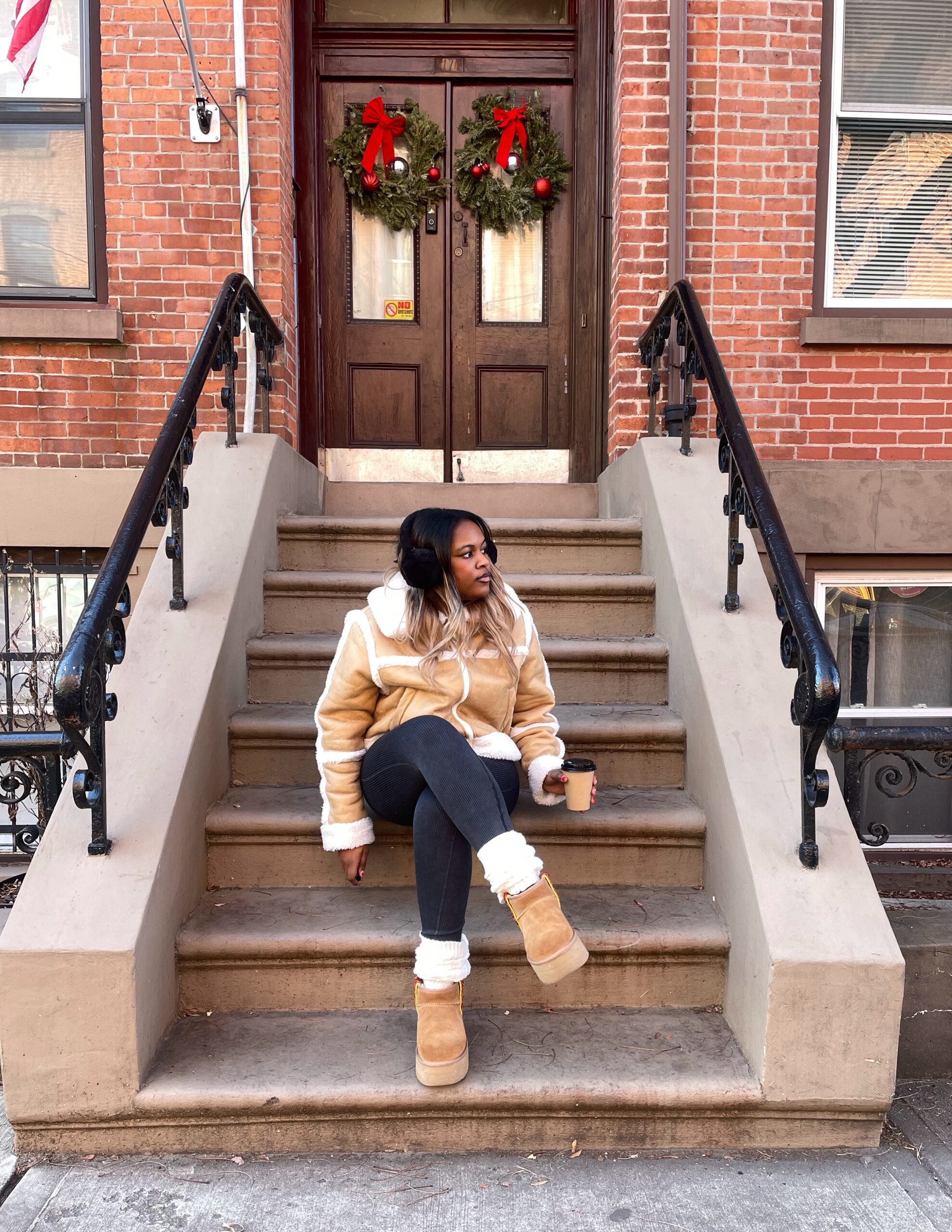 girl sitting on stairs out side with boots and a coat